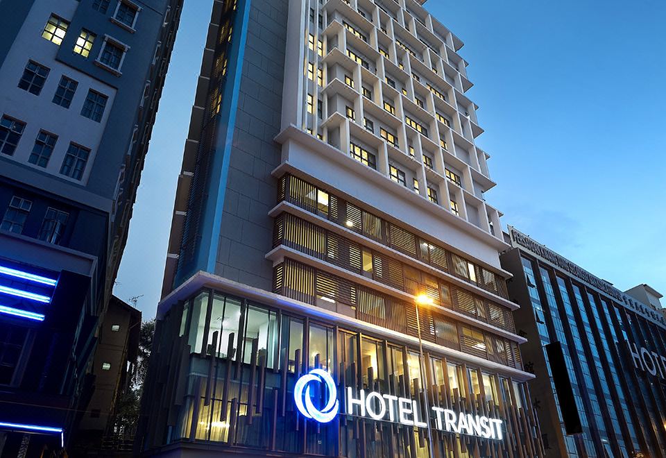 At night, there is a large office block with its name displayed on a building at Hotel Transit Kuala Lumpur