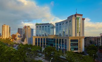 a modern , multi - story building with a green and yellow facade , surrounded by trees and other buildings at Holiday Inn Express