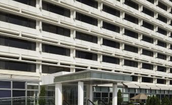 There is a large building with an entrance to the parking lot and other office buildings in front at Marco Polo Hongkong Hotel