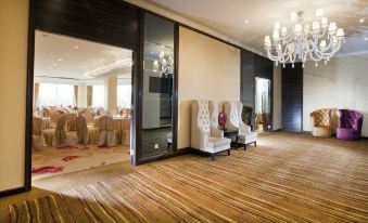 There is a spacious room with tables and chairs positioned in the center, accompanied by an elegant chandelier at Dorsett Shanghai