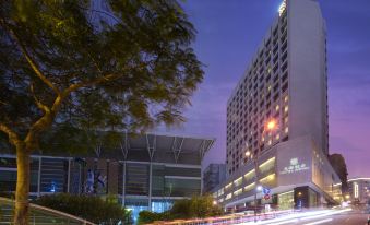 a modern hotel building lit up at night , with the exterior lit up and trees lining the street at Hotel Royal