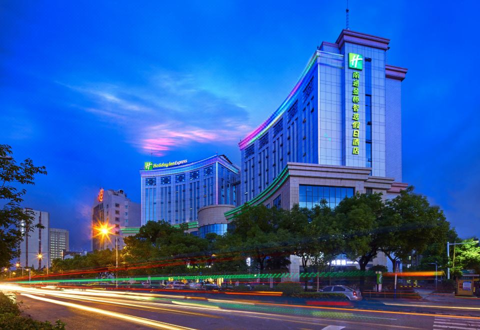 a large hotel building with a green and blue color scheme is lit up at night at Holiday Inn Express