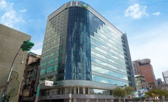 "a modern , blue - tinted building with a curved facade and a sign reading "" pan pacific hotel "" is surrounded by other buildings in a city" at Just Sleep Ximending