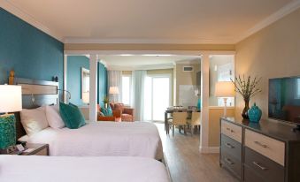 a modern hotel room with two beds , a kitchenette , and a balcony , decorated in blue and white colors at Bethany Beach Ocean Suites Residence Inn