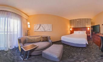 a modern hotel room with a round bed , couch , and nightstands , all decorated in warm colors at Courtyard New Carrollton Landover