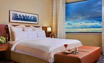 a large bed with white linens is in a room with a window and a table with a heart - shaped decoration at Montreal Airport Marriott in-Terminal Hotel