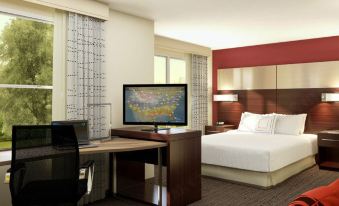 a modern hotel room with a large bed , desk , and flat screen tv , as well as a view of the city at Residence Inn Largo Medical Center Drive