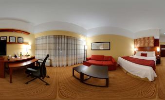 a 3 6 0 - degree panoramic view of a hotel room with a bed , couch , dining table , and chairs at Courtyard Troy