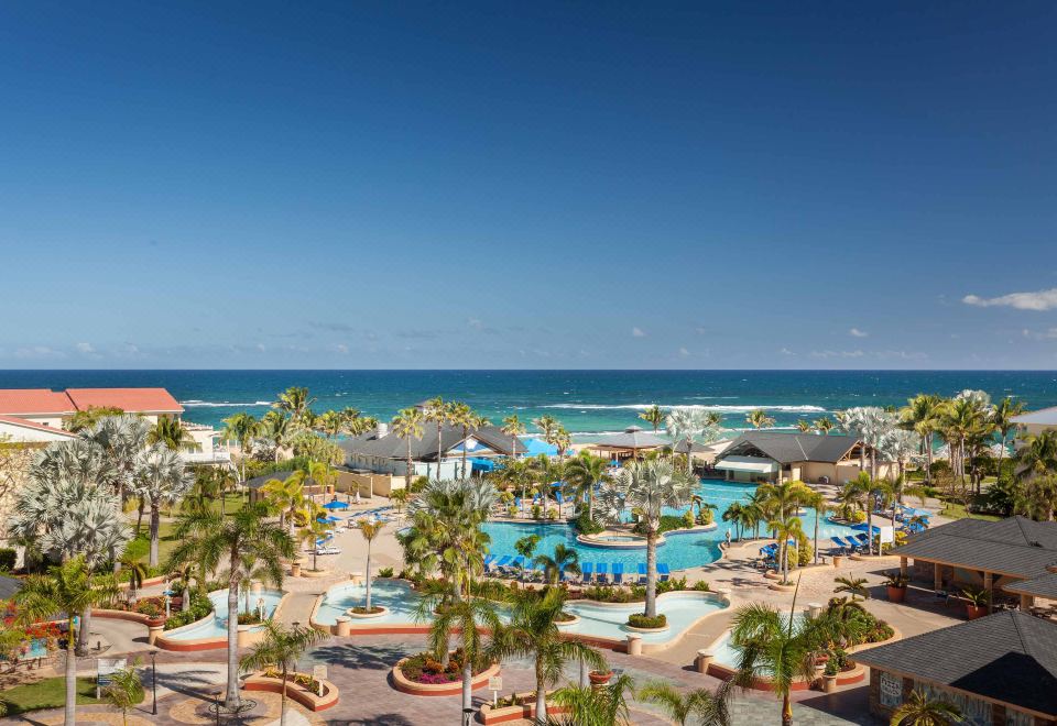 a resort with a pool and beach is shown from an aerial view , surrounded by palm trees and other buildings at St. Kitts Marriott Resort & the Royal Beach Casino