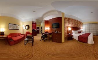 a modern hotel room with wooden flooring , red and gold accents , and a desk area at Courtyard Troy