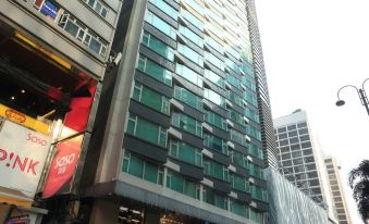 A tall building stands in front of a busy street, surrounded by other towering skyscrapers at Imperial Hotel