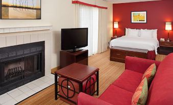 a cozy living room with a red couch , a fireplace , and a flat - screen tv . also a dining table in the room at Residence Inn Denver Tech Center