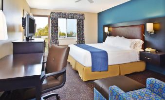 a hotel room with a king - sized bed , a couch , a chair , and a tv . also a desk in the room at Holiday Inn Express Mackinaw City