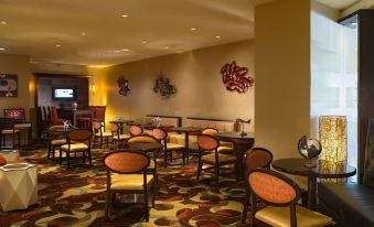 a dining area with several tables and chairs , some of which are covered in red and orange upholstery at Washington Dulles Airport Marriott