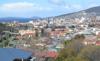 a cityscape with a view of the ocean and mountains , taken from a high vantage point at Hobart Tower Motel