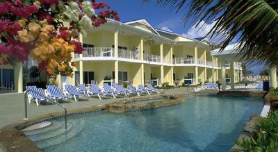 a large swimming pool surrounded by several lounge chairs and a building with multiple balconies at Wyndham Reef Resort Grand Cayman