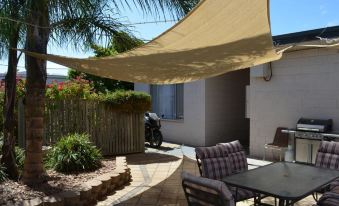 a patio with a dining table and chairs , as well as a motorcycle parked in the background at Kadina Village Motel