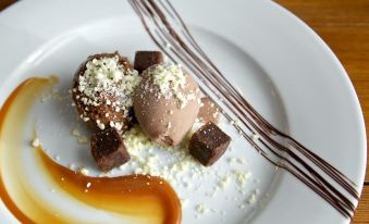 a white plate with three scoops of ice cream and chocolate sauce , accompanied by drizzled chocolate sauce at The Anchor Inn