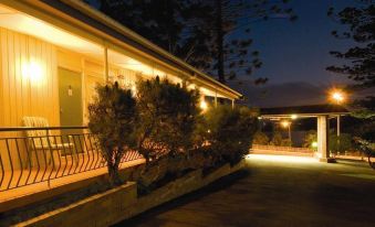 a house with a deck and tree lights is lit up at night , creating a cozy atmosphere at Waterview Gosford Motor Inn