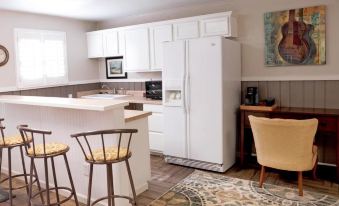 a kitchen with white cabinets , a refrigerator , and a dining table with chairs in front of it at Fiddler's Inn