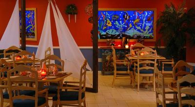 a dining area with wooden tables , chairs , and a blue mural on the wall , along with several christmas decorations at Wyndham Reef Resort Grand Cayman