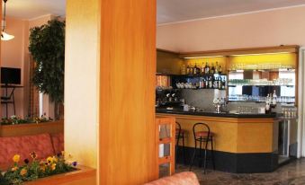 a bar area with various liquor bottles and glasses , as well as a dining table with chairs at Aries