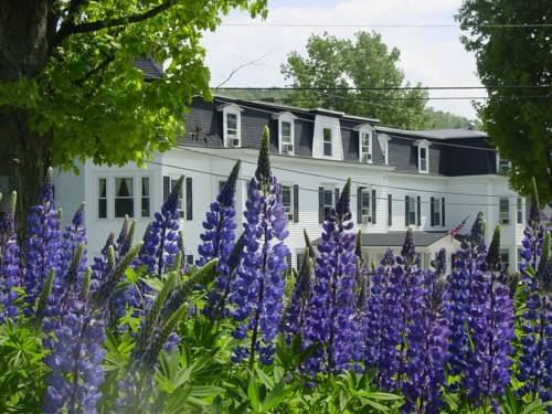 a house with a white exterior and purple flowers in the foreground , creating a picturesque scene at Sunset Hill House