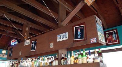 a wooden bar with various bottles and signs on the wall , creating an inviting atmosphere at Wyndham Reef Resort Grand Cayman