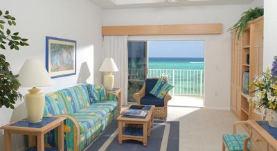 a living room with a couch , chair , and sliding glass door leading to a balcony overlooking the ocean at Wyndham Reef Resort Grand Cayman