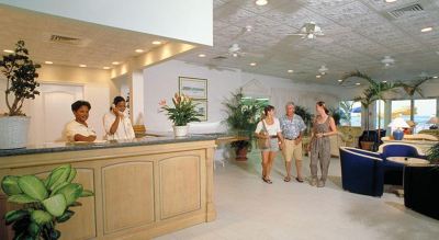 a group of people standing in a hotel lobby , with the reception desk providing information at Wyndham Reef Resort Grand Cayman
