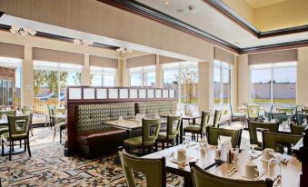 a modern , well - lit dining room with wooden tables and chairs arranged for guests to enjoy a meal at Hilton Garden Inn Merrillville