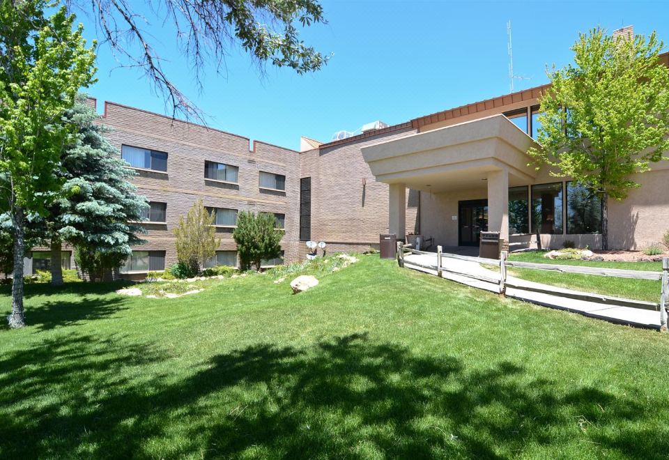 a large building with a green lawn in front of it , surrounded by trees and bushes at Squire Resort at The Grand Canyon, BW Signature Collection