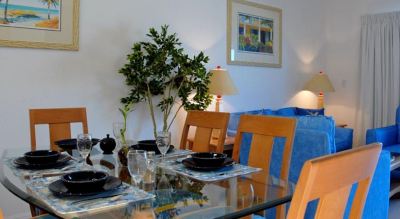 a dining room with a glass table , chairs , and a lamp , surrounded by a living room area at Wyndham Reef Resort Grand Cayman