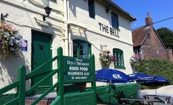 "a building with a sign that says "" the bell "" and an umbrella in front of it" at The Bell Inn