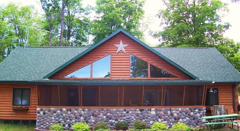 a wooden house with a stone facade and a large star on the roof is surrounded by greenery at Anderson's Northland Lodge