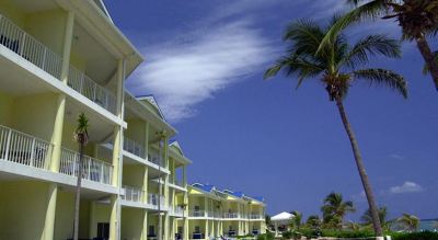 a row of blue and white buildings with balconies , surrounded by palm trees and a beach at Wyndham Reef Resort Grand Cayman