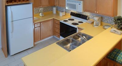 a kitchen with yellow countertops , white appliances , and stainless steel appliances on a stove at Wyndham Reef Resort Grand Cayman