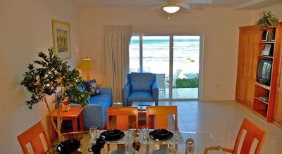 a living room with a dining table and chairs , and a view of the ocean at Wyndham Reef Resort Grand Cayman