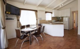 a dining room with a table and chairs , as well as a kitchen area with a stove and sink at Nrma Halls Gap Holiday Park
