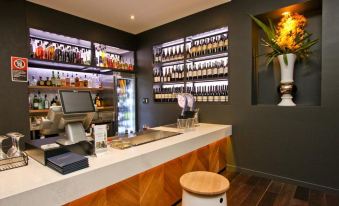 a modern bar with a wooden counter and stools , showcasing various bottles of wine on shelves behind it at The Star Apartments