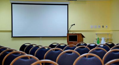 a conference room with rows of chairs and a projector screen , ready for a presentation or event at Wyndham Reef Resort Grand Cayman