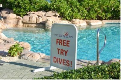 "a sign on the side of a swimming pool says "" free try dives !"" and has the words "" snorkeling in a cave .""" at Wyndham Reef Resort Grand Cayman