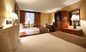 a hotel room with two beds , a desk , and a window , all set against the backdrop of a beige interior at Best Western the Inn at Ramsey