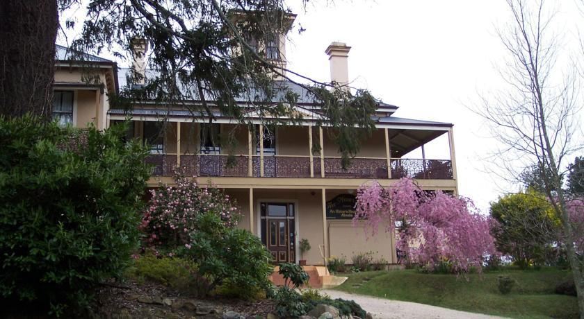 a large house with a brick facade and a balcony is surrounded by trees and bushes at Hotel Etico at Mount Victoria Manor