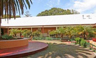 a courtyard surrounded by a brick building , with a fountain in the middle of the scene at Karma Rottnest