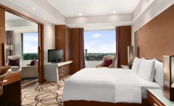 a modern hotel room with a large bed , white linens , and a balcony offering a view of the city at Hyatt Centric Janakpuri New Delhi