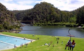 a group of people enjoying a day at a park by a lake , with some of them riding a water slide at Tamar Valley Resort Grindelwald