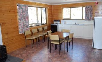a dining room with a table and chairs , as well as a kitchen area with a sink and cabinets at Gumleaves Bush Holidays