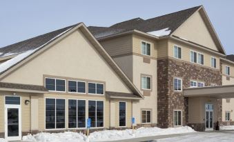 a large , modern building with multiple windows and a brown roof , situated in a snow - covered area at Grandstay Hotel Suites Thief River Falls