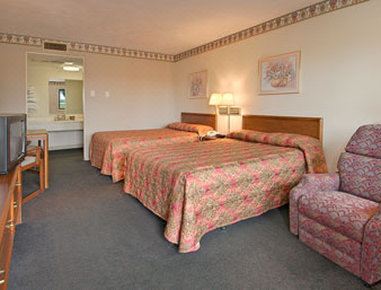 a hotel room with two beds , each made up with pink and green floral bedspreads , next to a nightstand with a lamp at Relax Inn